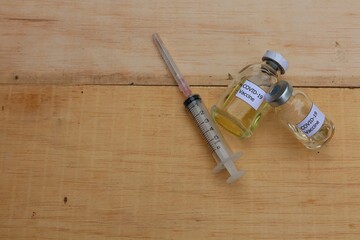 Coronavirus vaccine 2 doses in clear glass tubes. and disposable syringes on a wooden table background