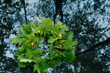 wreath of oak and fern leaves with candles in water. old national tradition, pagan holiday Ivan Kupala. Summer Solstice Day, Midsummer. wiccan symbol and rituals - obrazy, fototapety, plakaty