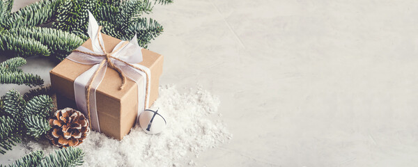 Christmas gift box in the snow on gray background. Christmas decor, winter mood, holiday decoration.