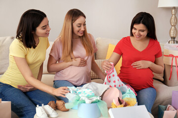 Happy pregnant women spending time together in living room after shopping