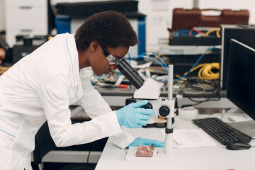 Naklejka na ściany i meble Scientist african american woman working in laboratory with electronic tech instruments and microscope. Research and development of electronic devices by color black woman.