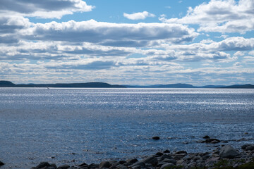 Many clouds with blue sky over the sea with mountains and rocks