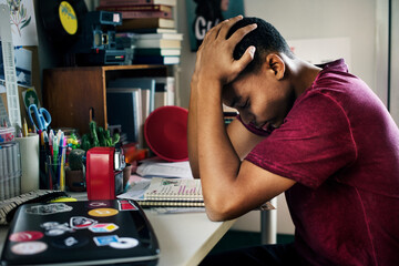 Teenage boy in a bedroom doing work stressed out and frustrated