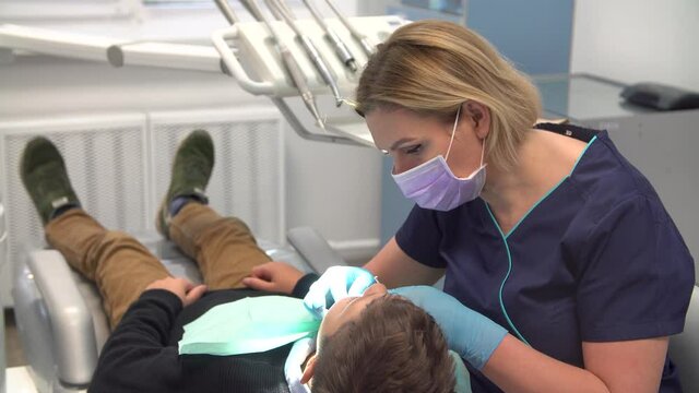 Dentist at work examines teenage boy