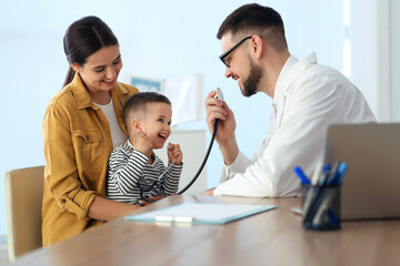 Mother and son visiting pediatrician in hospital. Doctor playing with little boy
