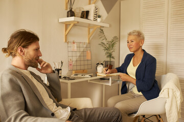Indoor shot of thoughtful young male with beard biting nails having deep in thoughts look,...