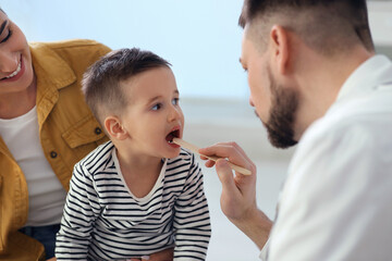 Mother and son visiting pediatrician in hospital. Doctor examining little boy