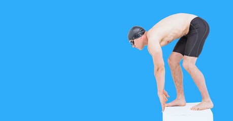 Composition of male swimmer on starting block with copy space isolated on blue background