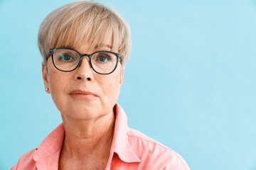 European mature woman in eyeglasses posing and looking at camera