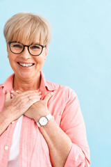 European mature woman smiling and holding hands on her chest