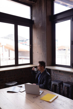 Caucasian businessman drinking coffee while looking out of the window at a cafe