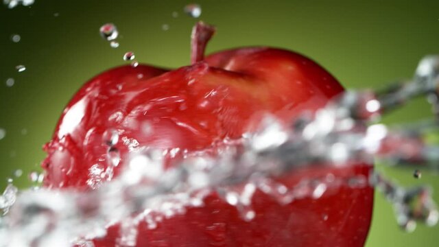 Super slow motion of rotating whole red apple with water splashing around. Filmed on high speed cinema camera, 1000 fps.