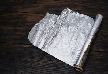 Aluminium foil roll on wooden table. For cooking.