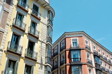 Fototapeta na wymiar Classical yellow and red buildings with elegant metallic balconies in Chueca district downtown Madrid, Spain