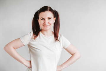 Beautiful woman with pigtails and a funny face wearing a T-shirt on a white background. Copy, empty space