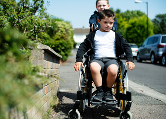 Boy pushing his brother in a wheelchair