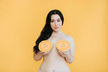 Woman holding cantaloupes over her breasts