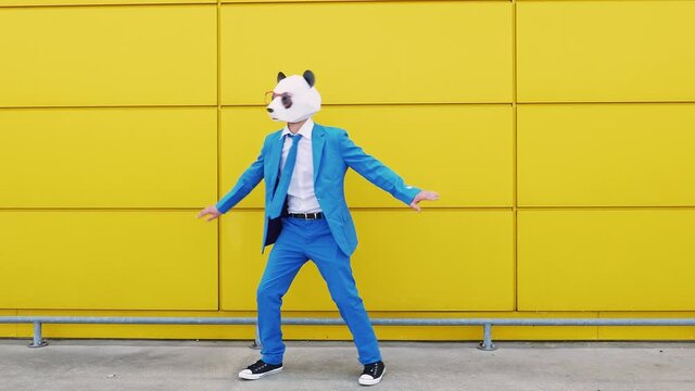 Business couple wearing animal masks dancing in front of yellow wall
