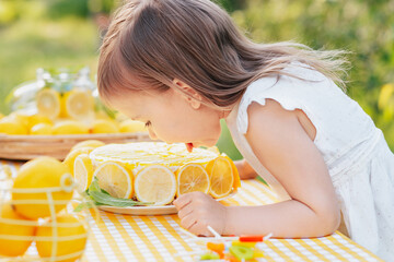 girl eating lemon Birthday cake. Lemonade birthday party at summer park. food, celebration and...