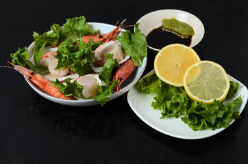 Natural raw scallop with boiled shrimp in the sink in a ceramic bowl with lettuce leaves and sauce on a dark background.