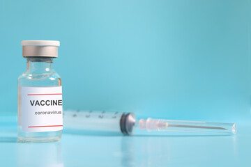 Glass vials containing liquid medical vaccine used to shot for injection treatment with blurred needle syringe on blue background and copy space, vaccination and immunization care for preventing coron