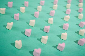 Candy of different colors on a turquoise background, a heart texture on Valentine's Day