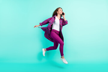 Full length body size view of attractive trendy cheery girl jumping calling phone isolated over bright teal color background