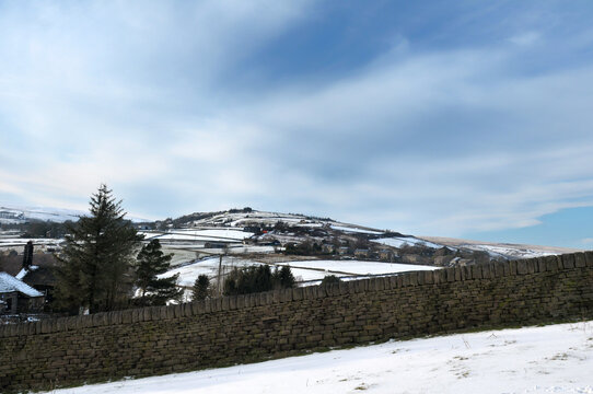snow covered pennine landscape with a view of fields and houses in heptonstall in calderdale west yorkshire surrounded by a stone wall