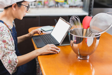 Businesswoman baker working on with laptop bakery equipment on table.