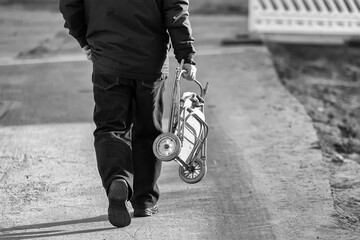 Salty spring day. A man in a black jacket and trousers walks along the asphalt road. In his hands...