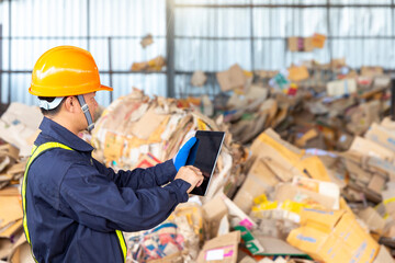 Engineer in a paper recycling plant. Employees in a paper recycling plant use a tablet. - obrazy, fototapety, plakaty