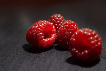 four fresh juicy berries on a black wooden table close up