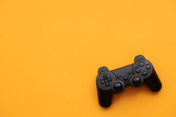 Black video game controller on a bright yellow background