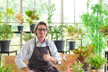 Portrait of happy senior man gardening wearing glasses and denim apron. Showing thumbs up, smiling...