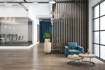 Stylish sunny office waiting area with blue armchair and light wooden coffee table, stylish partition and separated work place behind a glass wall