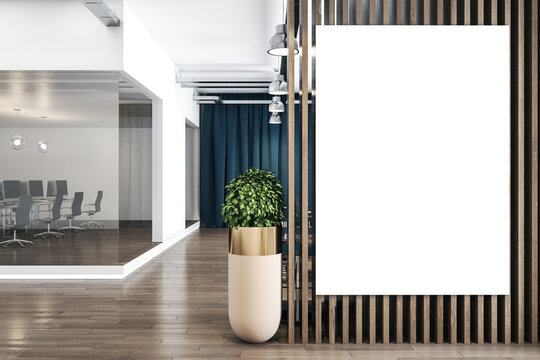 Blank white poster on wooden partition in stylish office space with tree in a flowerpot on wooden parquet and work place behind a glass wall. Mockup