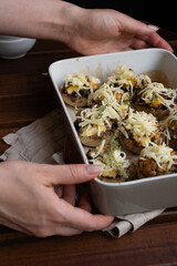 Woman's hands put a form with baked mushrooms. Low-carb diet.