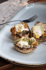 Baked mushrooms with cheese and meat on grey plate. Low-carb diet.