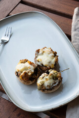 Baked mushrooms with cheese and meat on grey plate. Low-carb diet. Top view.