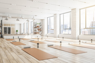 Concrete yoga gym interior with equipment, daylight and wooden flooring. Healthy lifestyle concept....