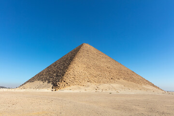 Fototapeta na wymiar Old big pyramid with the blue cloudless sky on the background.