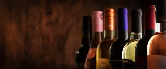 Rolgordijnen Wine bottles collection row in wine cellar, winery basement, bar or shop on dark wooden background © 5ph