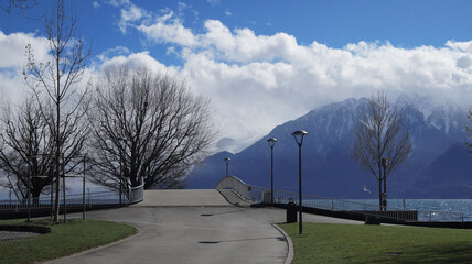 Beautiful landscape with the beach park, with grass, street lights, and a picturesque bridge with a background of snowy mountain and sky, Vevey, Sweden