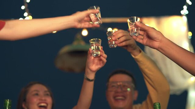 Diversity Asian millennial people friends enjoy dinner party with eat korean food barbecue grill and drink alcohol in shot glass at outdoor rooftop for meeting reunion and holiday celebration together