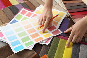Woman choosing among colorful fabric samples, closeup