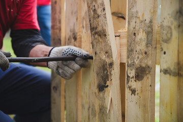 Working with wooden pallets. A man breaks a board in a pallet.