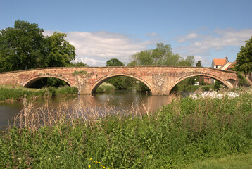 arched stone bridge over river Tyne Haddington in summer