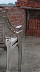 Vertical shot of two stacked chairs in the yard on a rainy day

