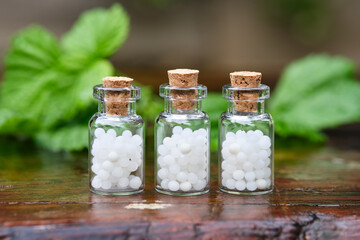 Three bottles of homeopathy globules. Bottles of homeopathic granules. Medicinal herbs on...