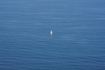 Obraz premium Lonely white sailing boat in the middle of a calm sea.